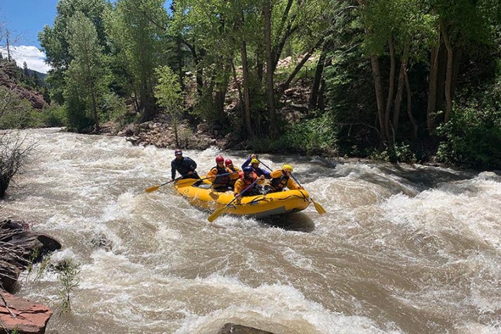 a man riding on the back of a boat next to a river