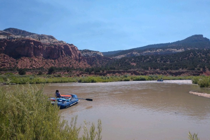 a boat floating along a river next to a body of water