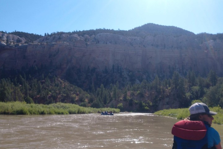 a man standing in front of a lake with a mountain in the background